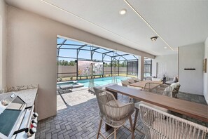 A covered outdoor area with a pool, seating, and a grill. - 10BR house sleeps 26 with private pool (Clermont)