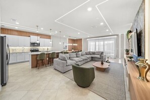 A modern living space with a kitchen, dining area, and a large grey sectional sofa. - 10BR house with private pool in clermont (Clermont)