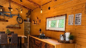 Et hyggeligt køkken i sommerhusstil med trævægge, et spiseområde med stole og et vindue med udsigt til naturen.