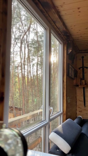 A cabin interior with a large window, a wooden ceiling, and a bench. - Willa na Drzewie - Leśna Przystań (Rudka Gołębska)