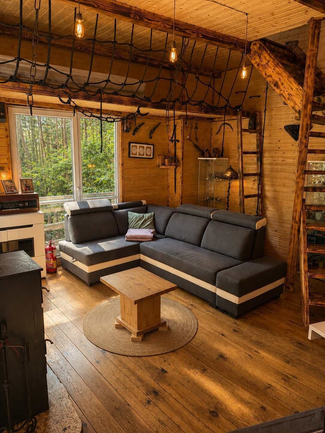 A cozy cabin interior with a sectional sofa, a wooden coffee table, and a rustic ceiling with hanging lights.