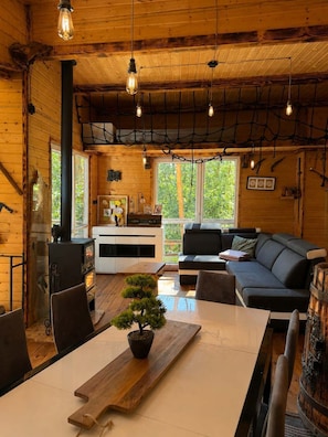 A cozy cabin interior with a wooden interior, a fireplace, a dining area, and a sofa.