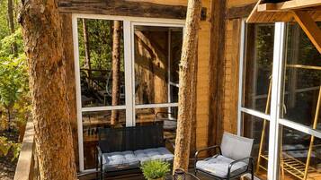 Une cabane en bois avec une terrasse, un canapé et une table agrémentée d’une plante.
