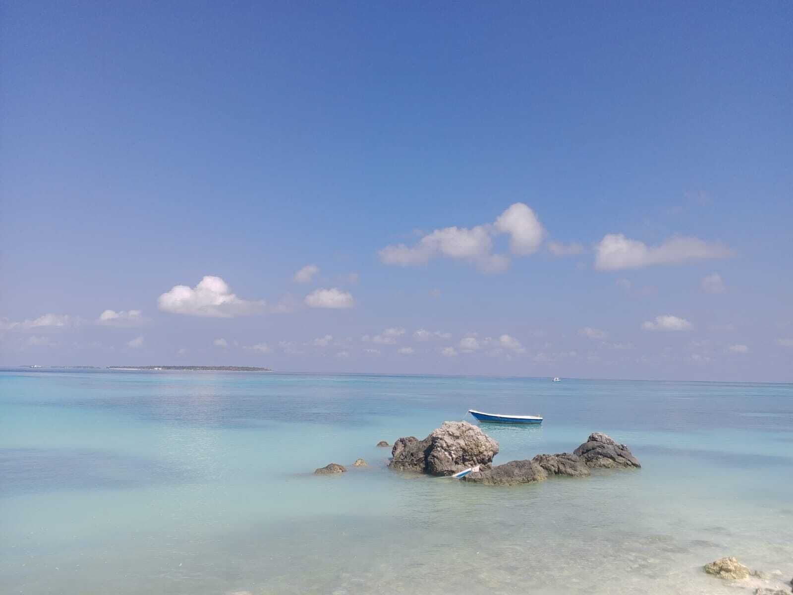 Ein klares türkisblaues Meer mit ruhiger Wasseroberfläche, ein kleines Boot und Felsen.