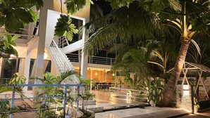 A modern building with a white staircase, outdoor seating area, and lush greenery. - Oceana Surf Maldives (Kudahuvadhoo)
