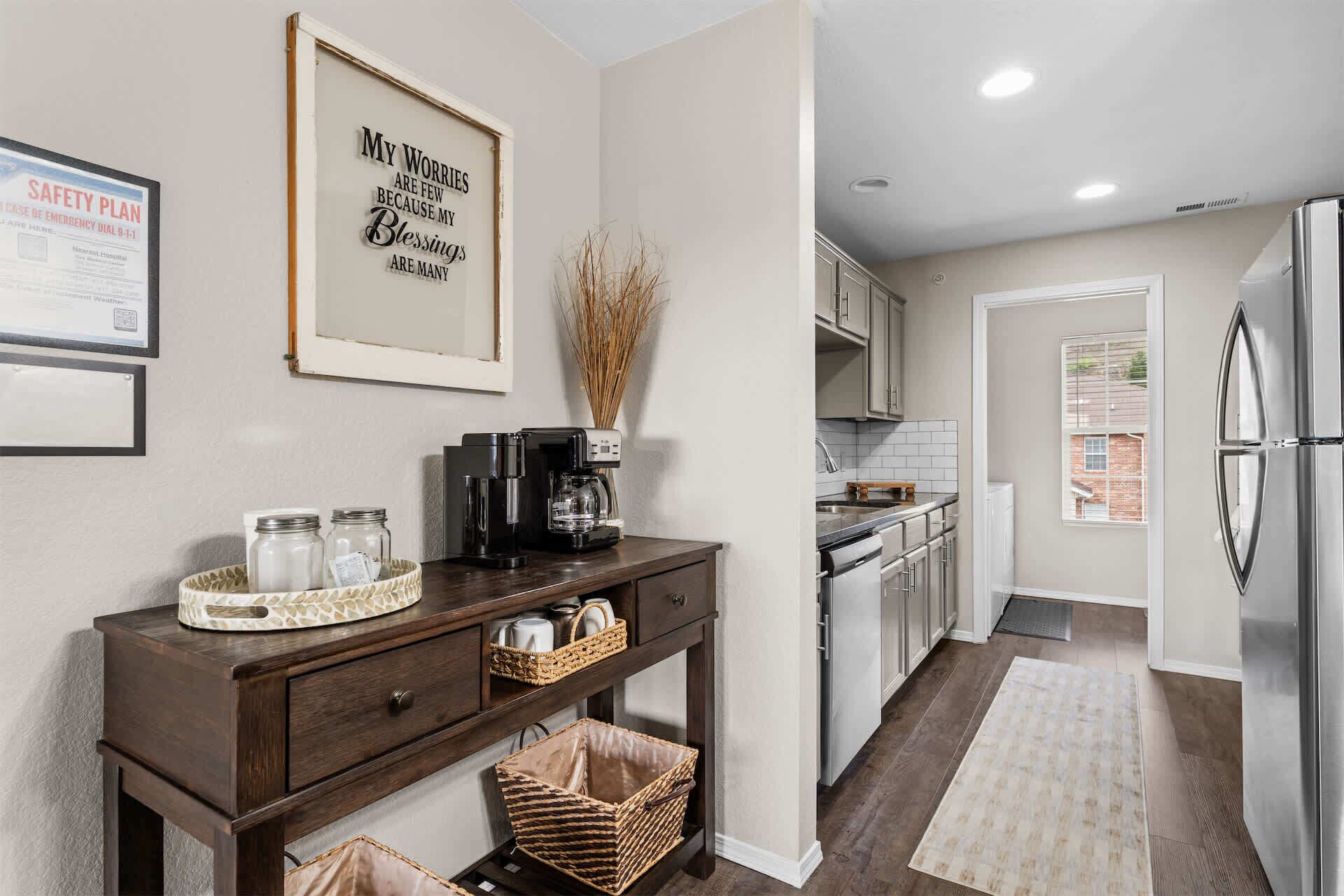 A kitchen with a coffee maker, a framed inspirational quote, and a refrigerator.