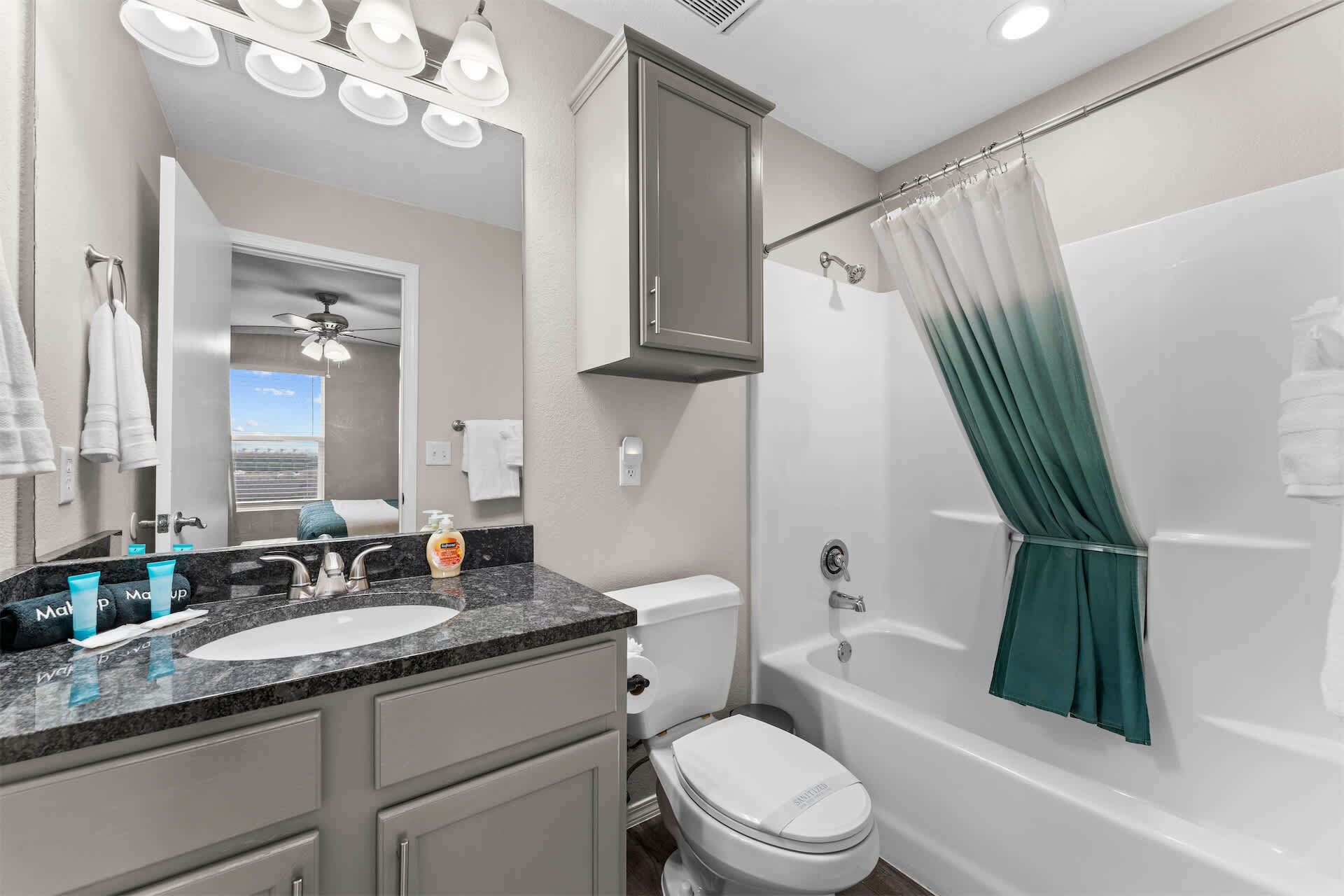 A bathroom with a double sink, a toilet, a bathtub, and a shower curtain.