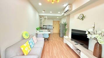 Uma sala de estar moderna com sofá, TV e plantas decorativas.