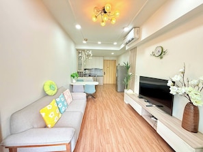 A modern living room with a sofa, TV, and decorative plants.