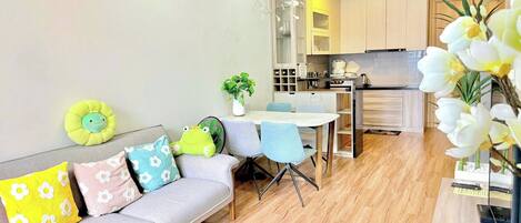 A modern living room with a sofa, a dining table, and a kitchen in the background.