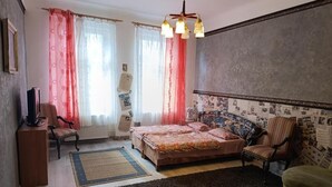 Un dormitorio con una cama, dos sillas, un radiador y una ventana con cortinas.