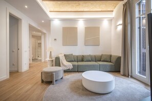 Un salon moderne avec un canapé d’angle, une table basse ronde et une lampe.