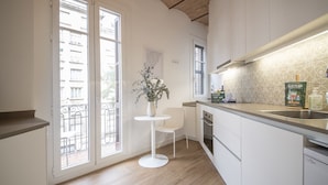 Une cuisine moderne avec un plan de travail blanc, une petite table ronde et une plante en pot.