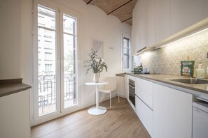 Une cuisine moderne avec un plan de travail blanc, une petite table ronde et une plante en pot.