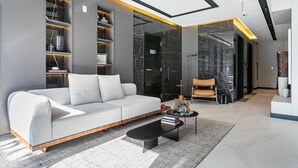 Un salon moderne avec un canapé gris, une table basse noire et une bibliothèque.