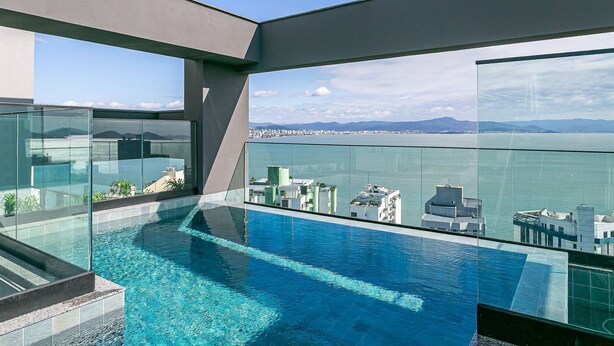 Une piscine à débordement située sur le toit, offrant une vue dégagée sur les gratte-ciel de la ville et les montagnes à l’horizon.