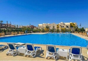 Ein Swimmingpool mit Liegestühlen und blauem Himmel.