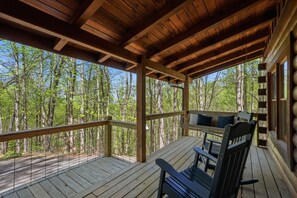 A wooden deck with a view of a forest, a bench, and a window with a view. - Be Still | MTN Views, Hot Tub, Grill, Fireplace! (Sevierville)