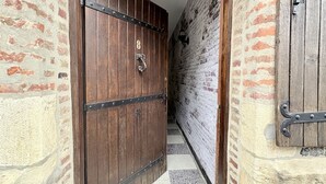 Un couloir avec une porte en bois, des murs en briques et un sol carrelé.