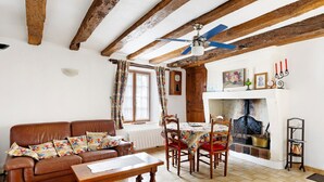 Ein gemütliches Wohnzimmer mit Kamin, Holzbalken, einer Couch und einem Esstisch.