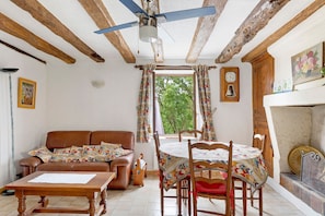 Une piĂšce avec un plafond en bois, une table Ă manger avec des chaises, un canapĂ©, une cheminĂ©e et une vue par la fenĂȘtre.