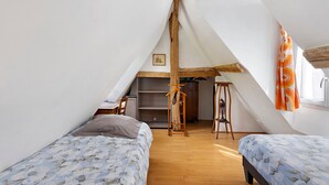 Ein Schlafzimmer mit zwei Betten, Holzboden, einem Kleiderschrank und einem kleinen Schreibtisch.