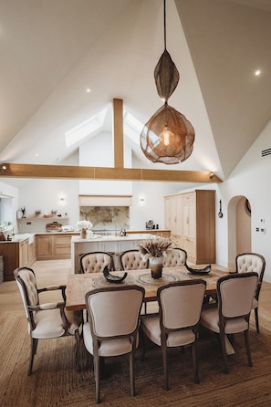 A spacious kitchen with a high ceiling, wooden beams, and a central island with seating.