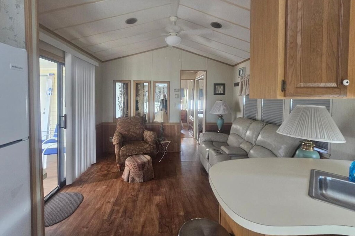 A compact living space with a kitchenette, a sofa, a chair, and a dining table.
