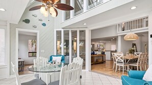 Un ambiente spazioso con zona pranzo, un divano blu e una ventola a soffitto.