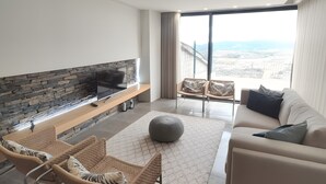 A modern living room with a stone fireplace, a flat-screen TV, a sofa, and a view of the city. - Local Accommodation – Douro Barcos House (Barcos)