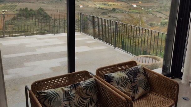 A balcony with wicker furniture and a view of a rural landscape. - Local Accommodation – Douro Barcos House (Barcos)