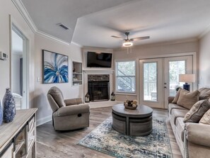 A living room with a fireplace, a ceiling fan, and a television mounted on the wall. - Tranquility Skies | MTN View, Sauna, Jacuzzi, MORE (Gatlinburg)