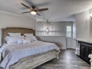 A bedroom with a large bed, a ceiling fan, a chandelier, and a window. - Tranquility Skies | MTN View, Sauna, Jacuzzi, MORE (Gatlinburg)