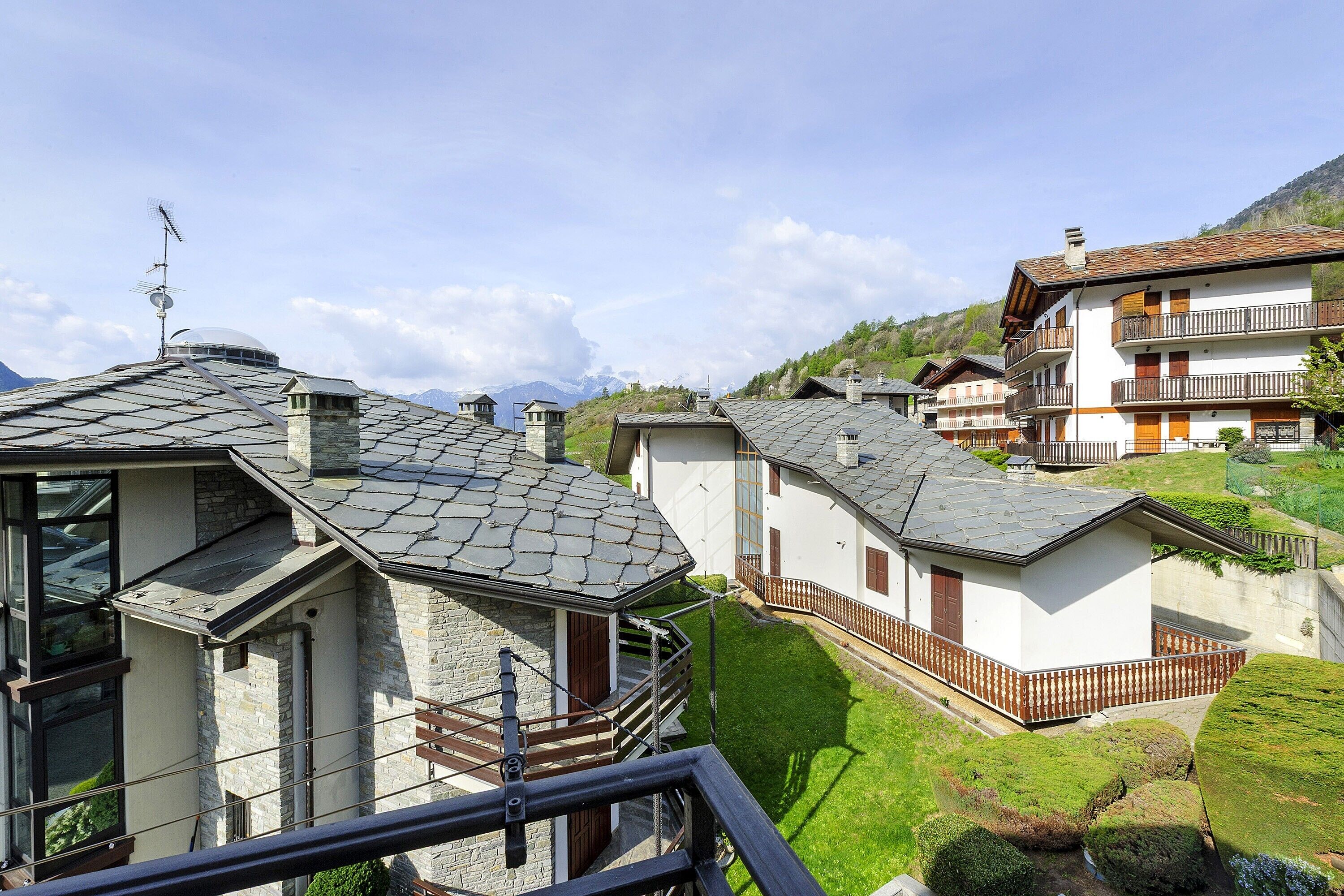 Ett bostadsområde med hus som har fasader av sten, balkonger och en bergig bakgrund.