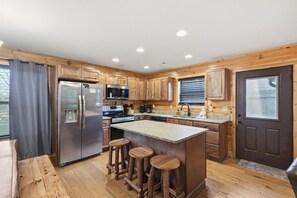 A kitchen with wooden cabinets, a stainless steel refrigerator, a microwave, and a sink. - Memory Maker Lodge:Hot Tub, Multicade, Grill, MORE (Gatlinburg)
