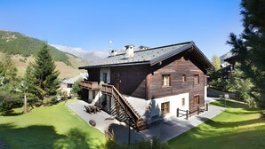Un chalet en bois doté d’un escalier, d’une terrasse et offrant une vue sur les montagnes.