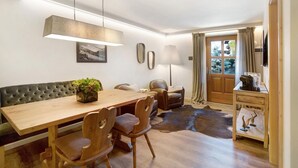 Un coin repas comprenant une table en bois, des chaises en cuir, un banc, une plante en pot et un tapis en peau de vache.