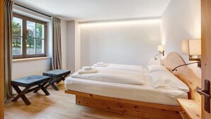 Une chambre à coucher avec un lit en bois, une petite table et une fenêtre avec des rideaux.