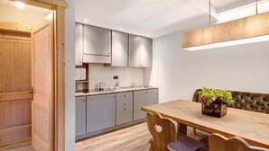 Une cuisine moderne avec des meubles de couleur grise, une table à manger en bois et un luminaire suspendu.