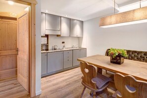 Una cocina moderna con armarios grises, una mesa de comedor de madera y una lámpara colgante.