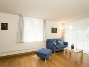 A living room with a sofa, ottoman, and a small table. - Chesa Quadrella by Interhome (Pontresina)