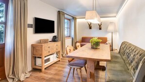 Ein gemütliches Zimmer mit einem Holztisch, einer Couch, einem Fernseher und einer Lampe.