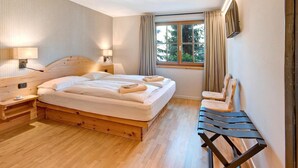 Ein Schlafzimmer mit einem hölzernen Bett, Nachttischlampen, einem Fenster mit Vorhängen und einer Holzbank.