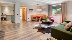 Ein modernes Wohnzimmer mit einem grünen Sofa, einem runden Couchtisch und einem Holzessttisch mit roten Stühlen.