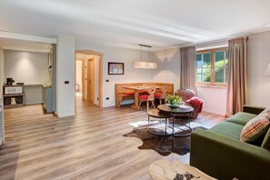 A modern living room with a green sofa, a round coffee table, and a wooden dining table with red chairs. - Apartment 'Superior 2-4' with Mountain View, Shared Garden and Wi-Fi (Teola)