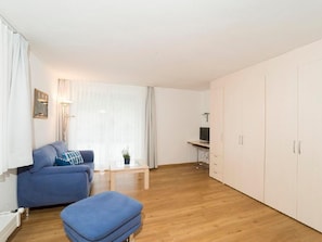 A room with a sofa, a small table, a TV on a stand, and a wardrobe. - Chesa Quadrella by Interhome (Pontresina)
