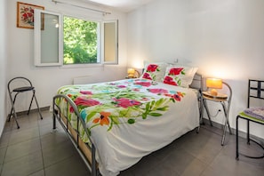 A bedroom with a bed, two nightstands, a window, and a chair.