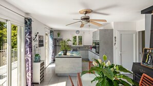 Eine moderne Küche mit einer zentralen Kochinsel, einem Essbereich mit Tisch und Stühlen sowie einem Deckenventilator.