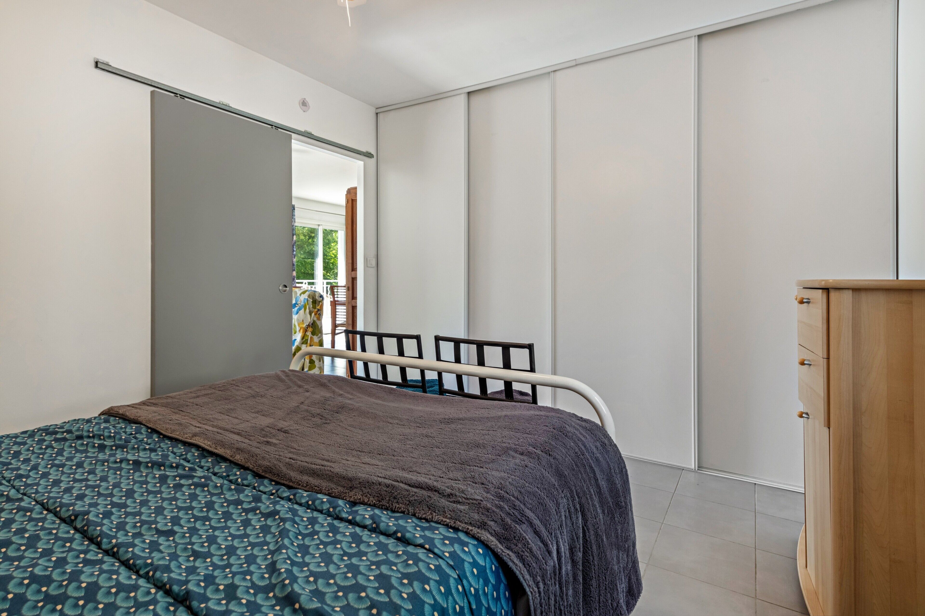 Een slaapkamer met een bed, een kledingkast en een schuifdeur naar een balkon.