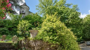 Eine Steinsäule mit einer Treppe, üppigem Grün und einer turmartigen Struktur im Hintergrund.